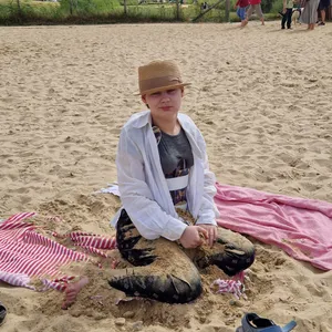 Ein Mädchen sitzt auf einer Decke im Sand